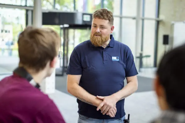 Medewerkers MBO Utrecht in gesprek met twee studenten in de hal van het schoolgebouw