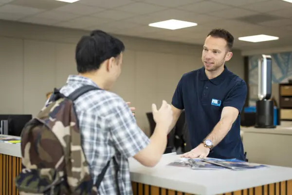 Medewerkers ontvangsbalie beantwoordt vragen van een student bij de balie