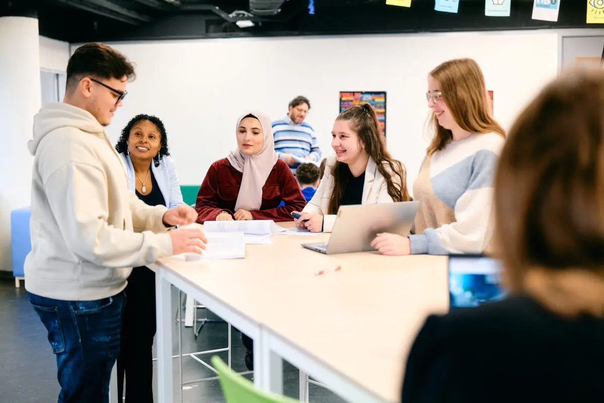 MBO-studenten Business Services rond een sta-tafel in gesprek met een docent
