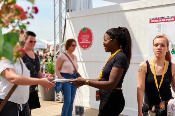 Mbo-studenten Evenementenorganisatie delen folders uit op een festival