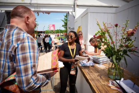 Gasten in gesprek met mbo-student Evenementenorganisatie op een festival waar deze student werkt