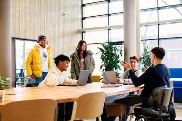 Studenten in gesprek rond een tafel in de kantine op school