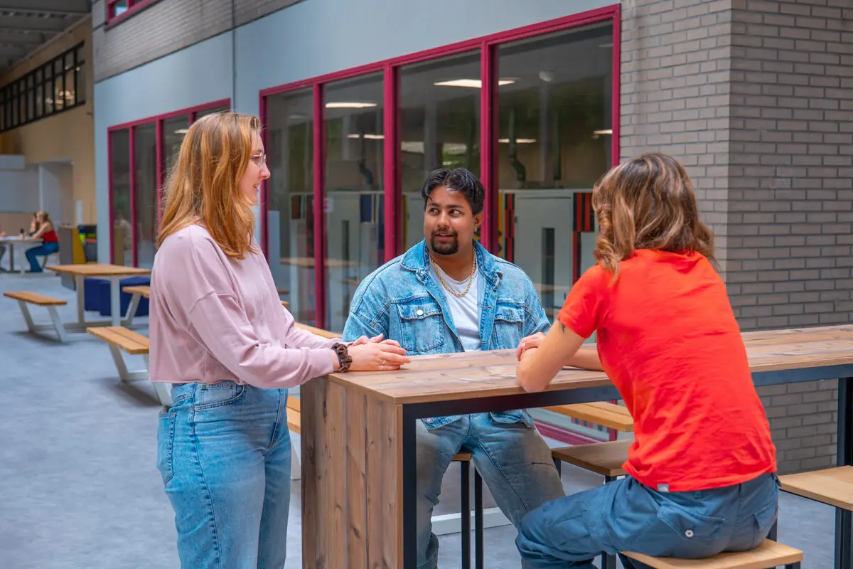 Drie studenten zijn in overleg in de centrale ruimte