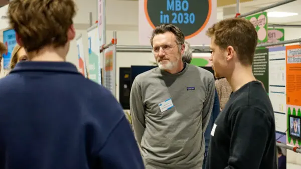 Een docent luistert aandachtig naar vragen op de Open Dag