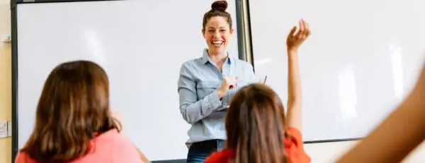 Onderwijsassistent van een Vrije school staat lachend voor de klas
