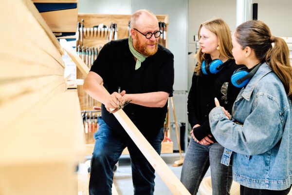 Docent geeft uitleg over hout aan mbo-studenten bouwkunde