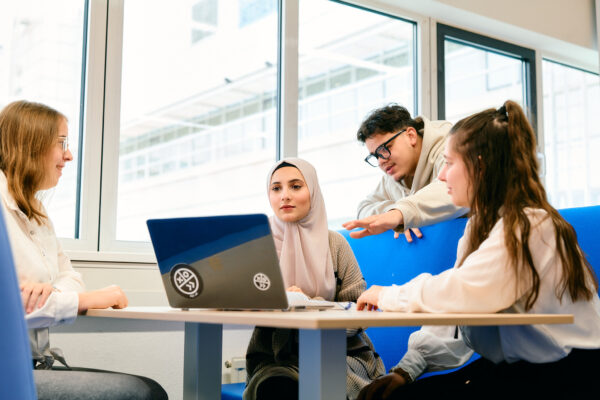 MBO-studenten Business Services en Recht, verzekeren en HR samen in overleg rond een laptop