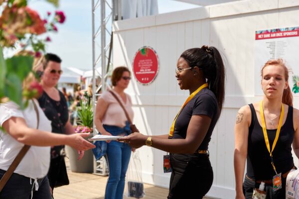 Mbo-studenten Evenementenorganisatie delen folders uit op een festival