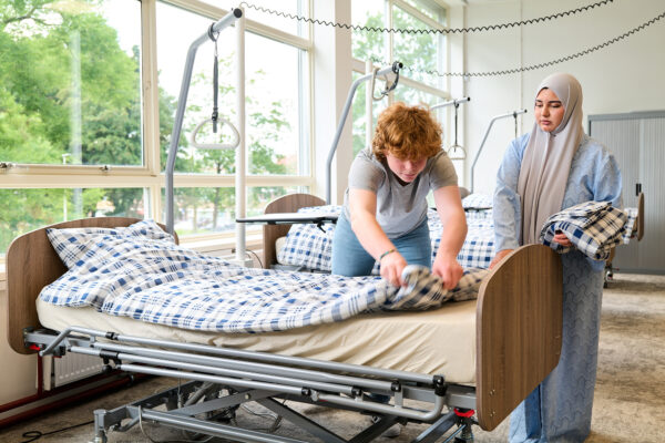 Studenten opleiding Zorg en Welzijn maken een bed op met z'n tweeën