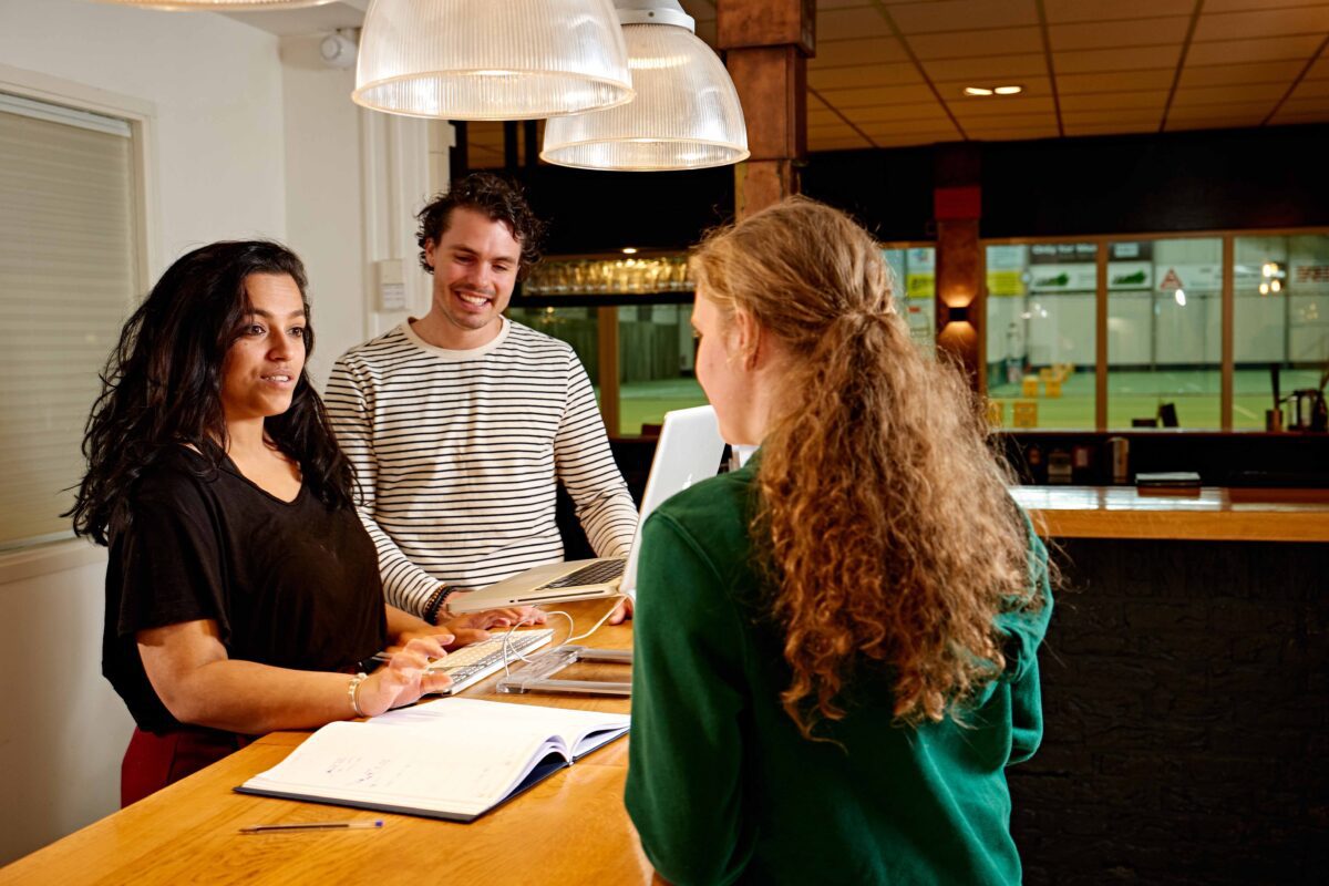 MBO student Toerisme en Horeca ontvangt gasten bij een balie