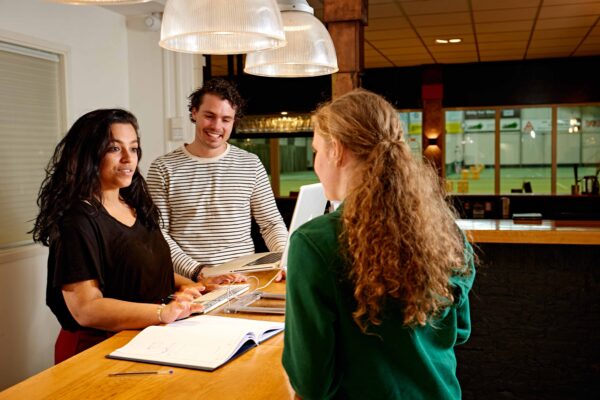 MBO student Toerisme en Horeca ontvangt gasten bij een balie