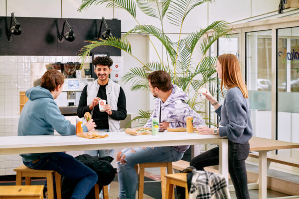 Mbo-studenten retail en commercie met elkaar in gesprek in de pauze rond een statafel