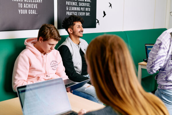 Mbo-studenten, twee zitten samen op een bank en een is achter een laptop aan het werk
