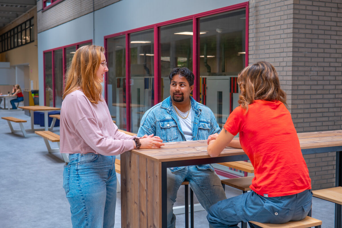 Drie studenten zijn in overleg in de centrale ruimte