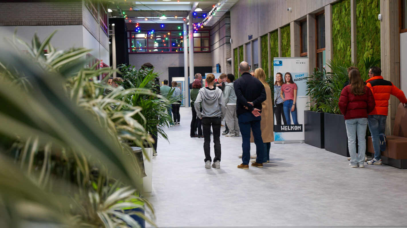 Ouders en studiekiezer kijken op afstand naar een demonstratie op de Open Dag
