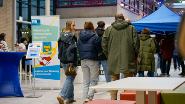 Twee studiekiezers lopen met ouder door de gang op de Open Dag