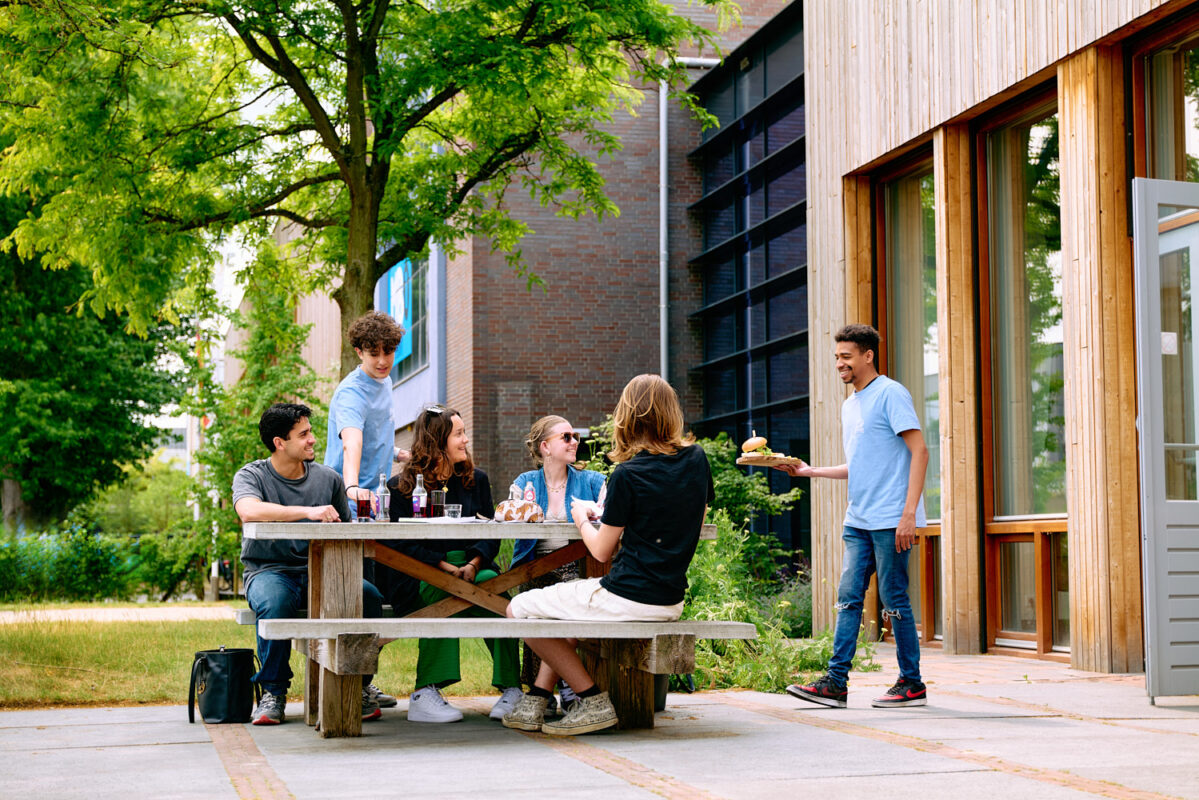Studenten serveren eten en drinken op het terras van de brasserie