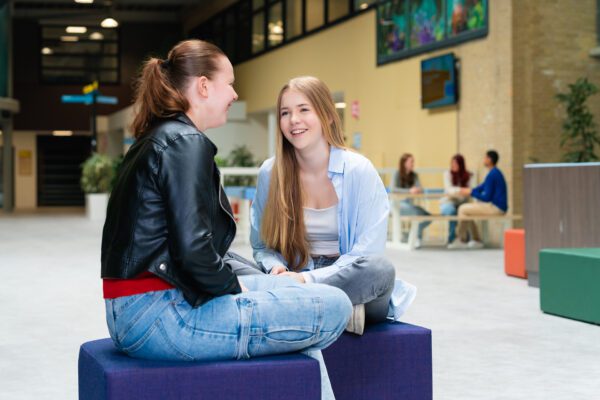 Twee studenten chillen op een blauwe zitblok